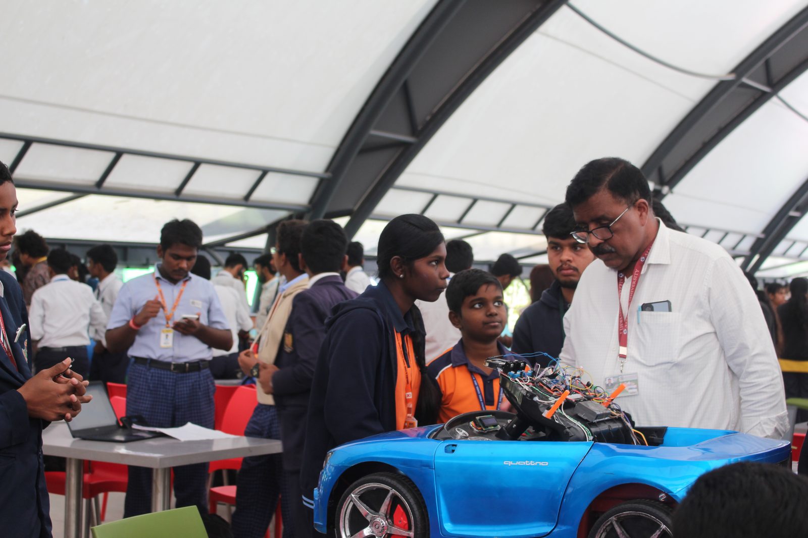 An Alliance University faculty member reviewing the Autopilot Car with MMS students