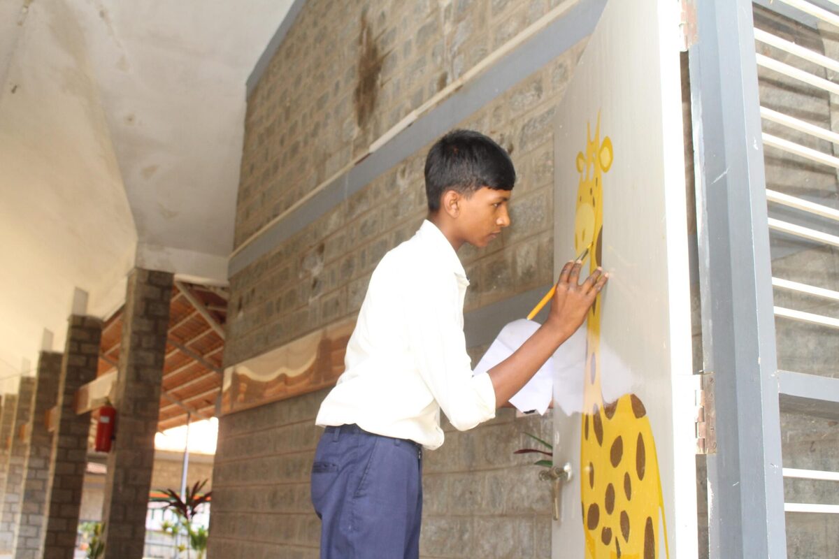 A student painting a colourful pattern on a corridor pillar