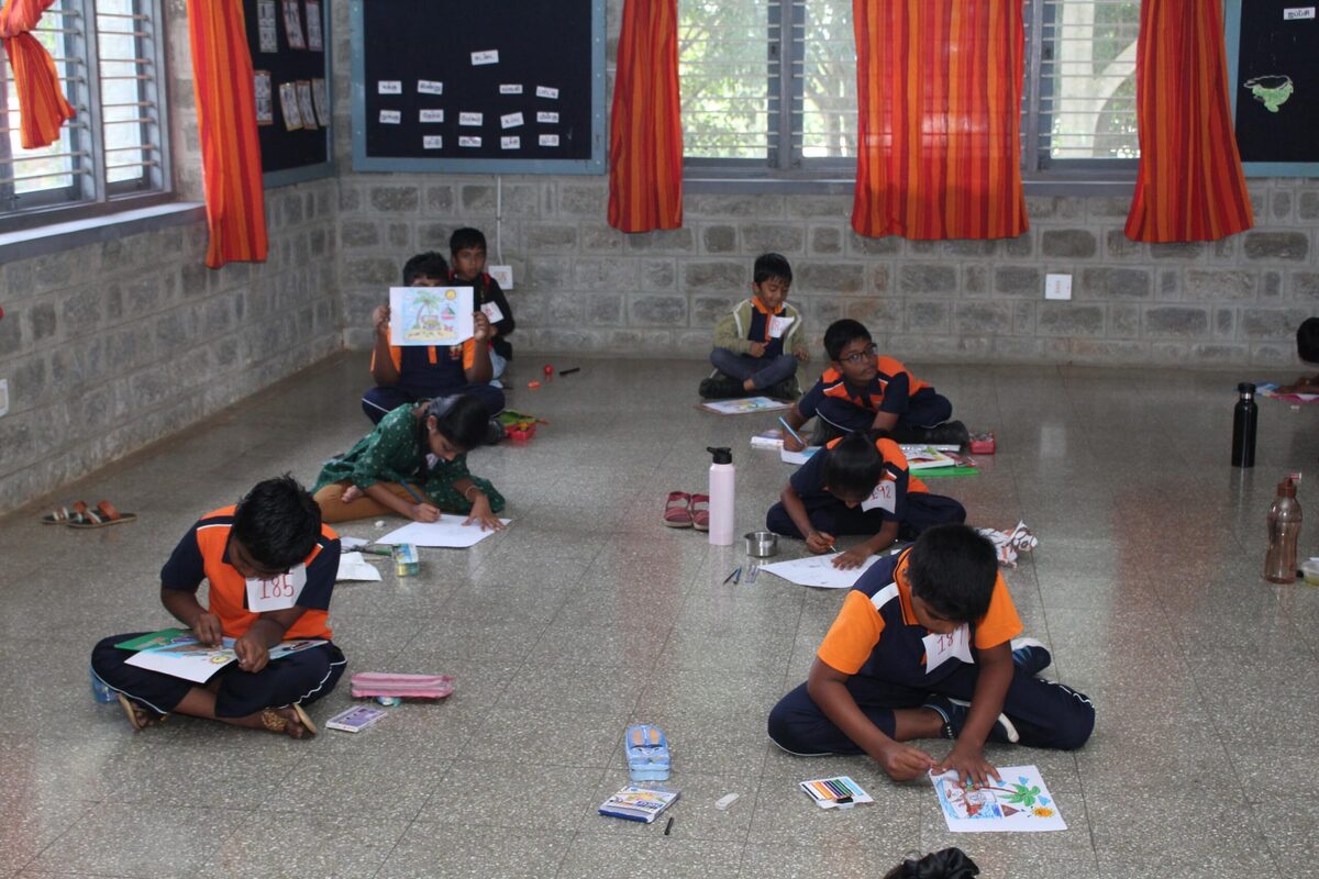 Students seated on the floor, engrossed in a drawing competition