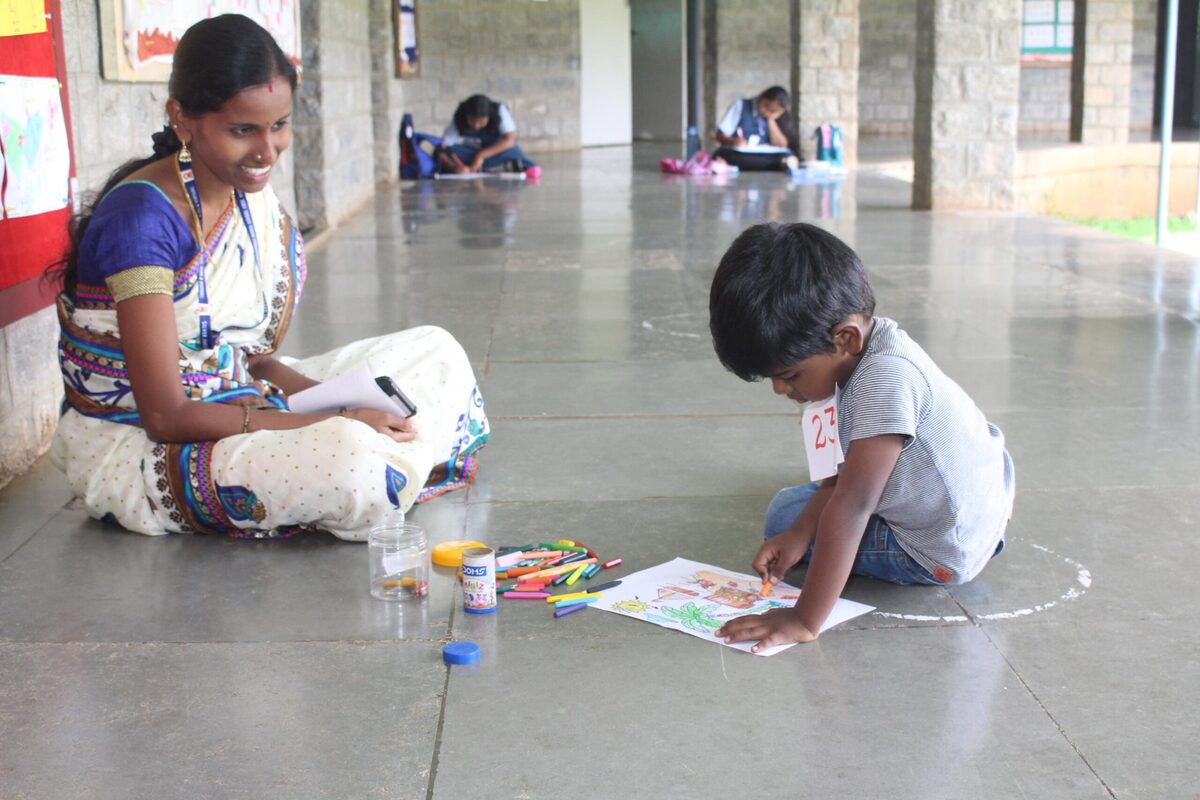 A mentor guiding a young participant during an art competition