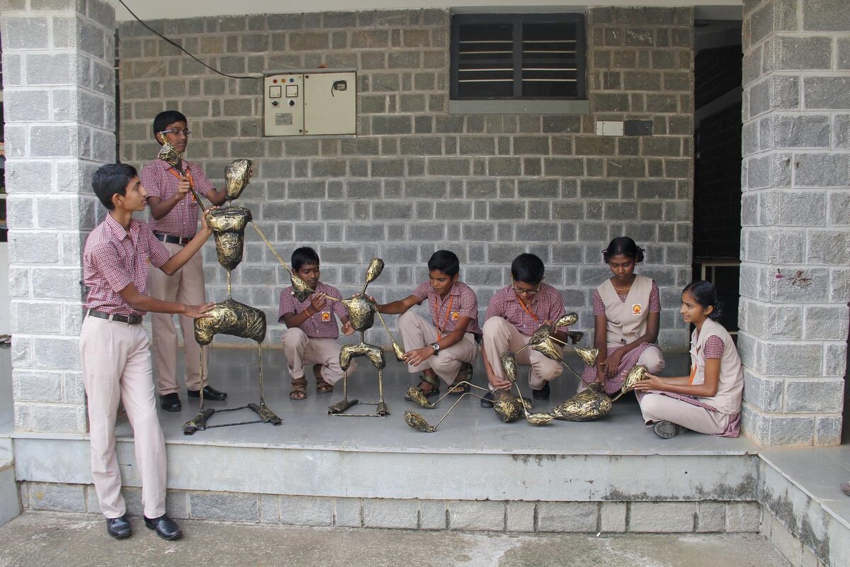 Students in traditional attire posing with handcrafted brass pot props