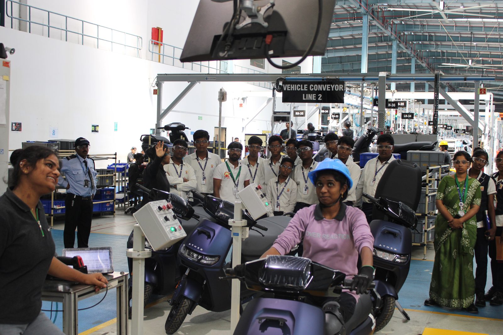 Students observing the vehicle conveyor line and a scooter test ride demonstration