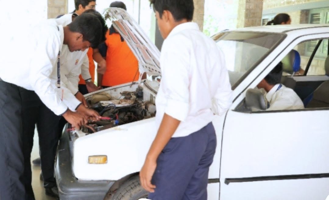 Students exploring an internal combustion engine bay with a teacher