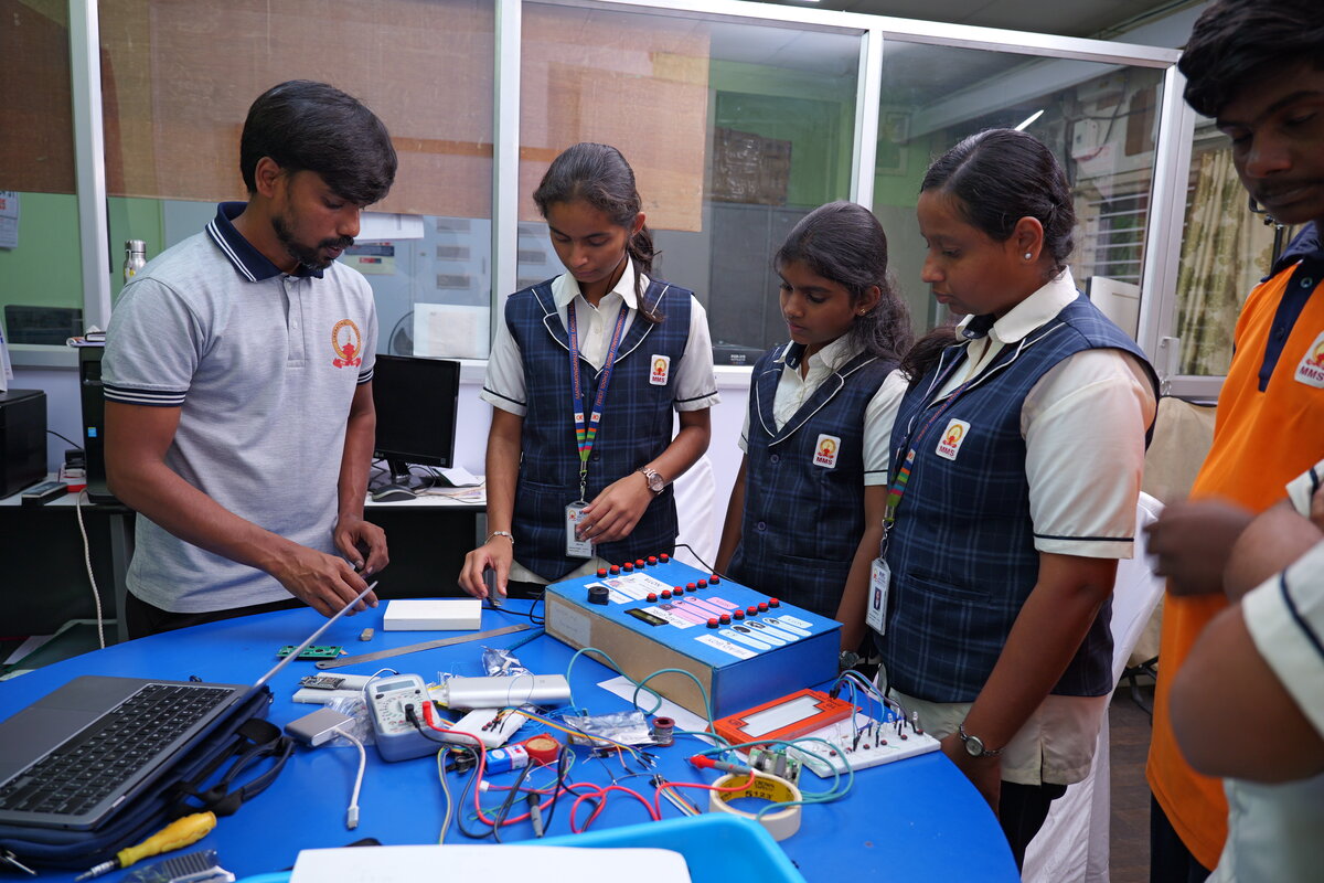 A teacher and students building the school's own electronic voting machine