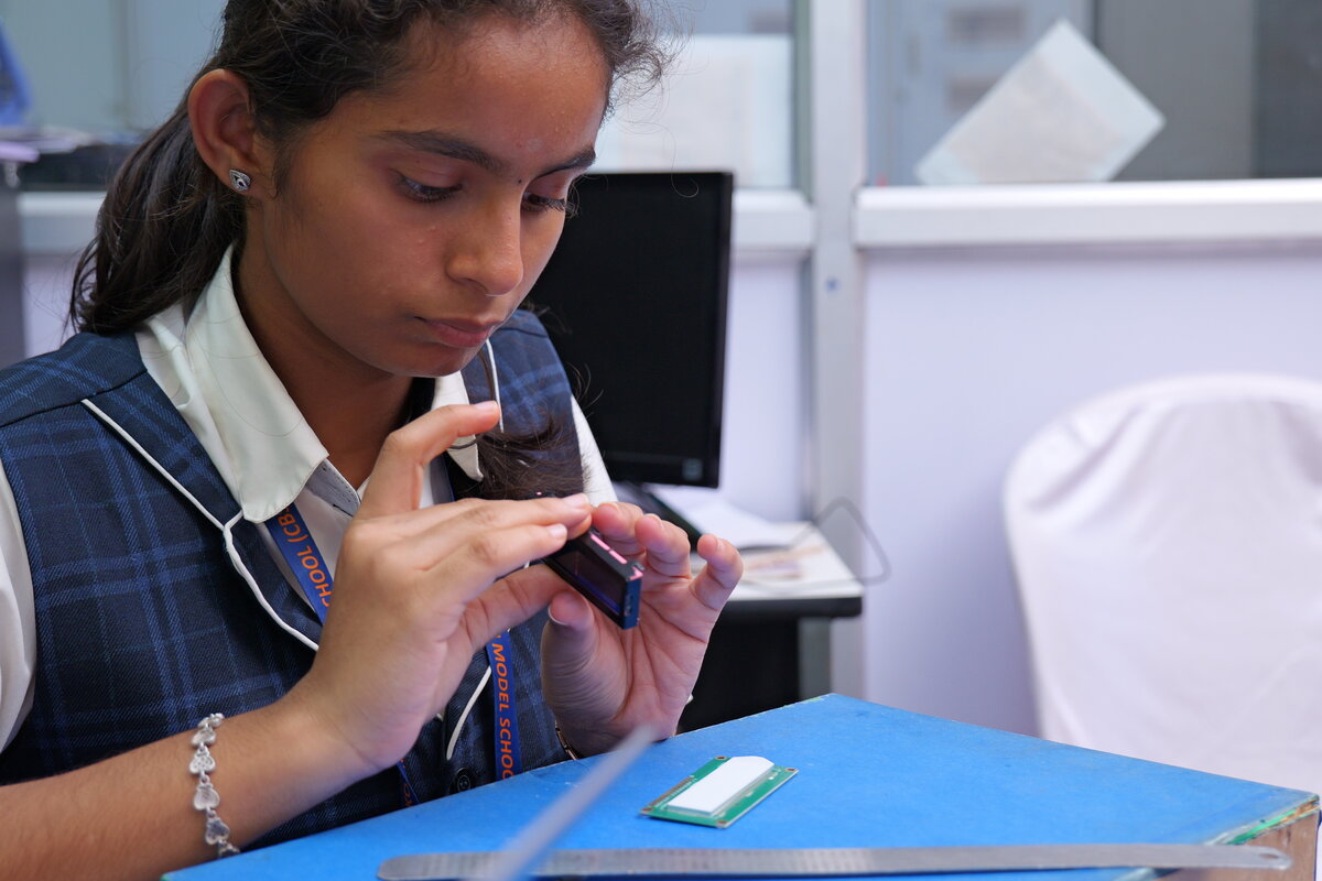 A student examining a small OLED display module for the circuit