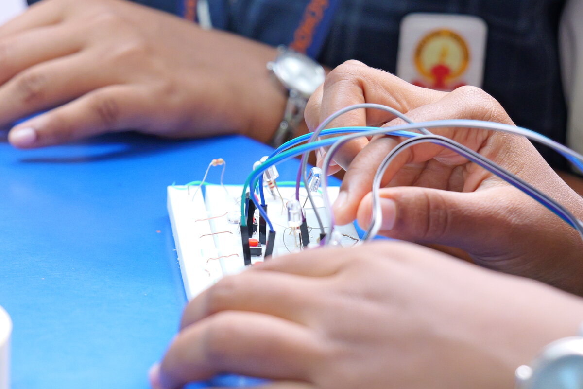 Close-up of students wiring sensors and LEDs onto a breadboard