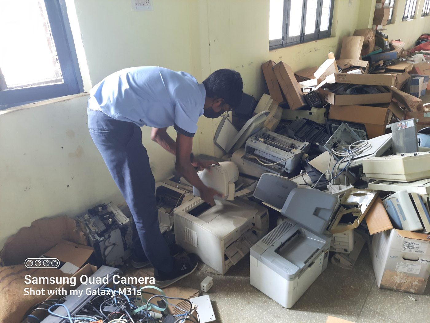 Student dismantling an old printer to recover reusable parts