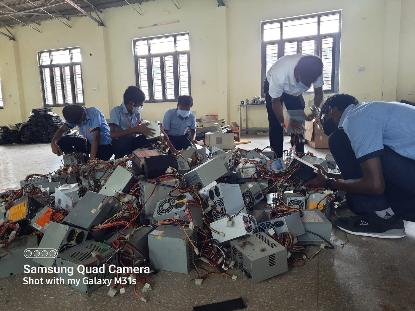 Students and staff working through a pile of scrapped power supply units