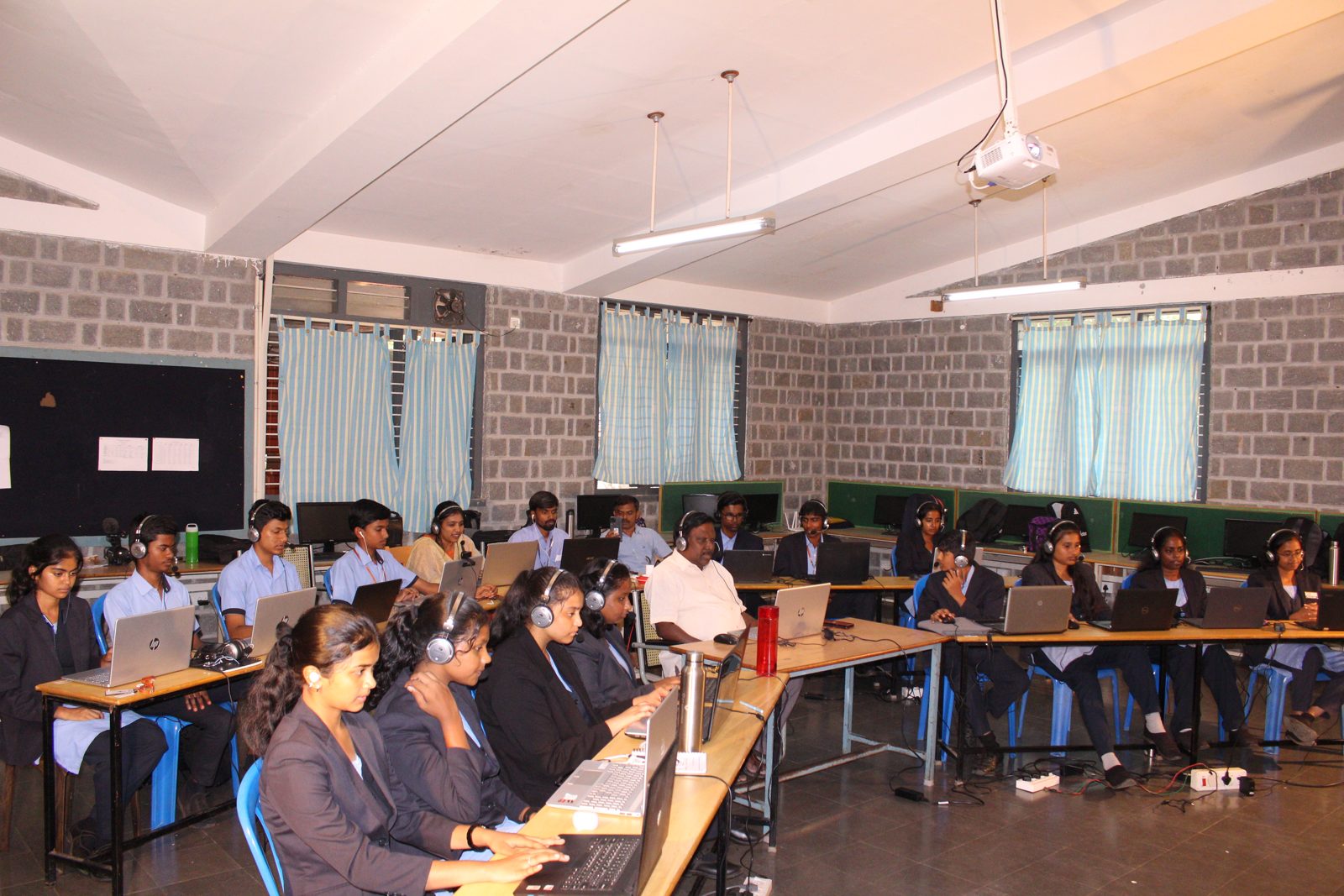 Students and staff seated with headsets and laptops in the Communication Lab during the Korea collaboration session