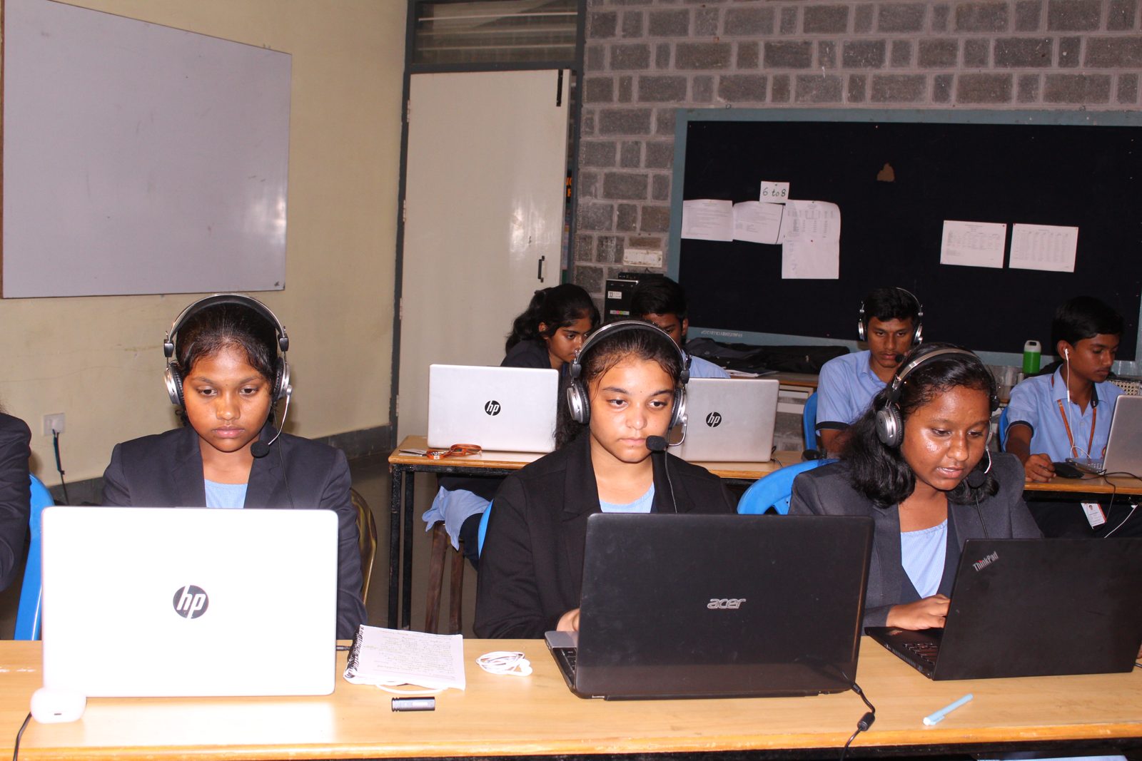 Three students with headsets and microphones at their laptops during the session