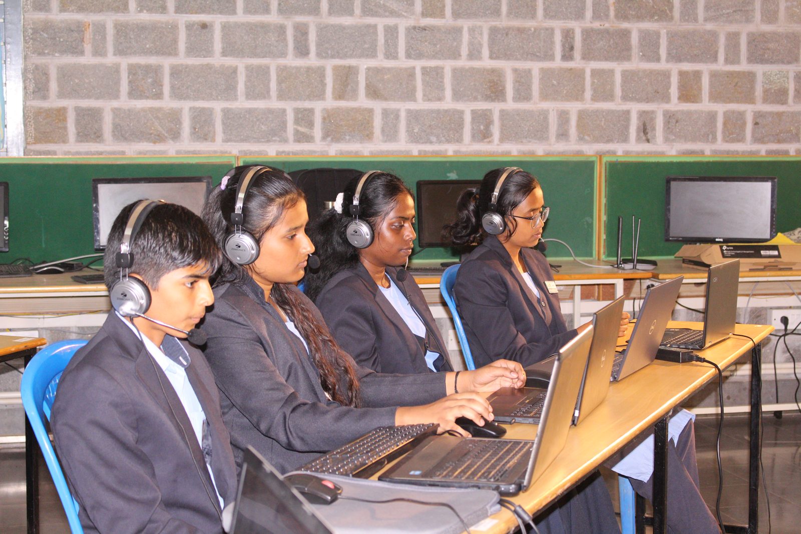 Four MMS students with headsets working on laptops during the live session