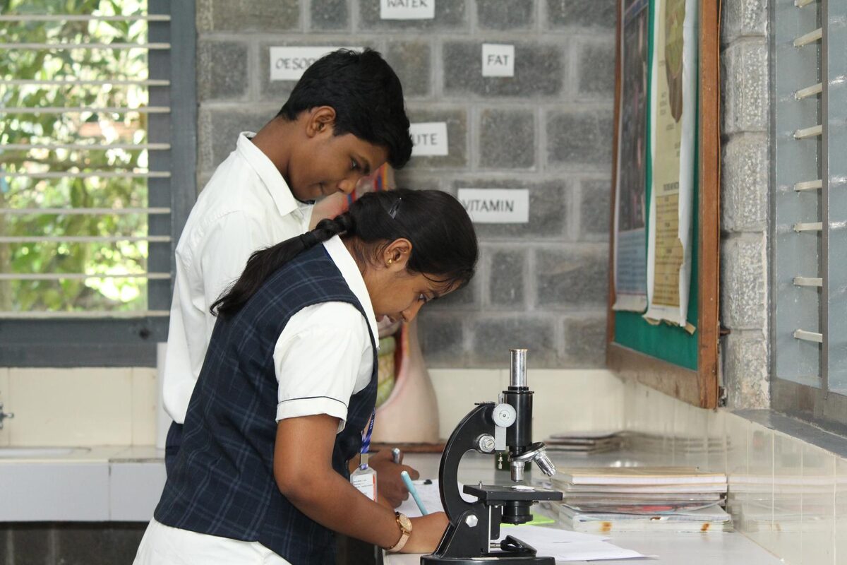 Students taking turns observing a prepared slide under the microscope