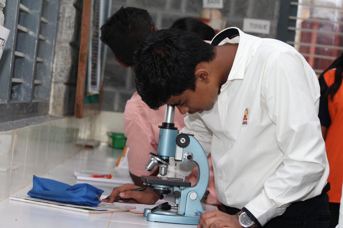 A student and teacher studying a slide under the microscope together