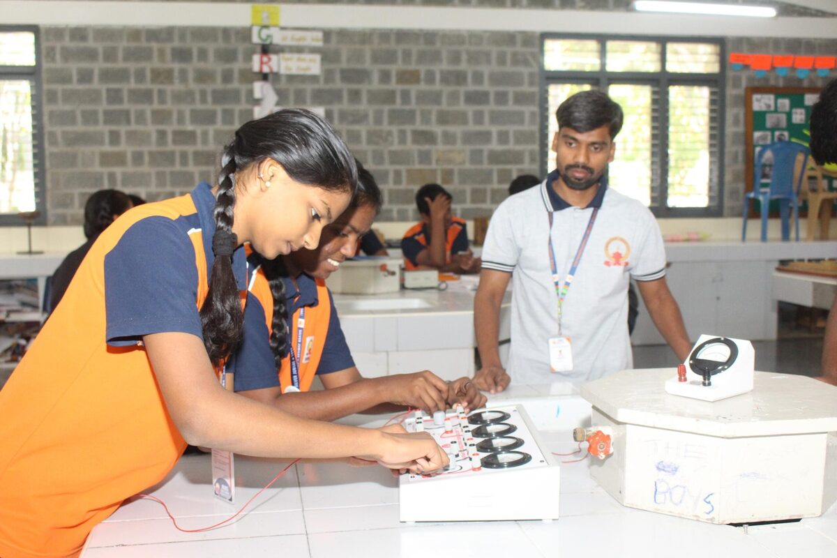 A student records circuit readings under staff guidance