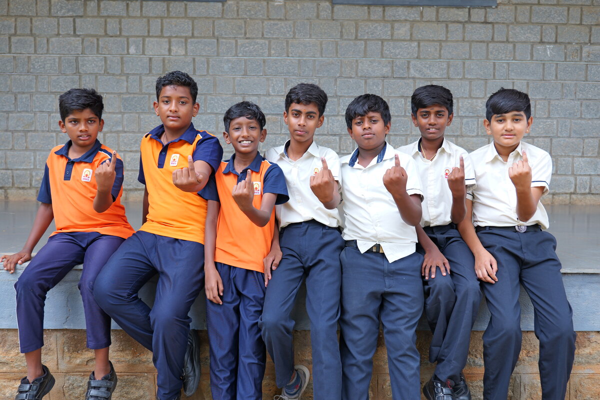 Seven students displaying their inked fingers after voting