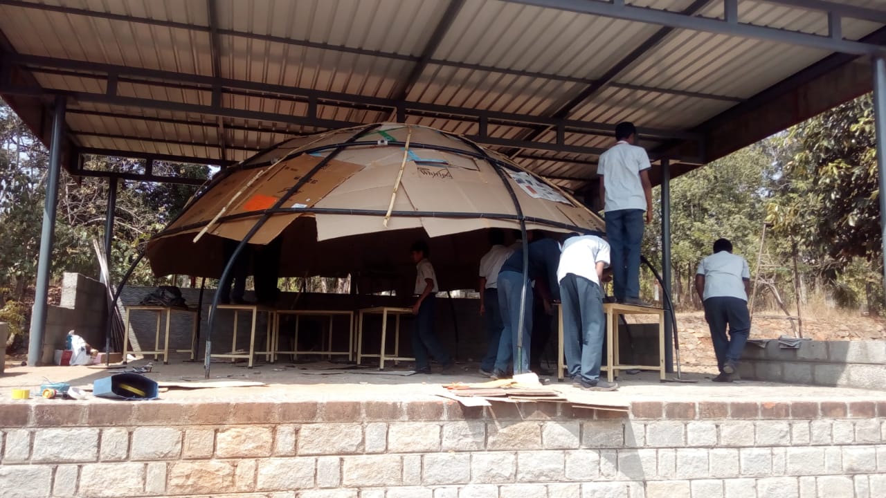The completed cardboard-panelled shell of the Version 2 planetarium, wide view with students working underneath