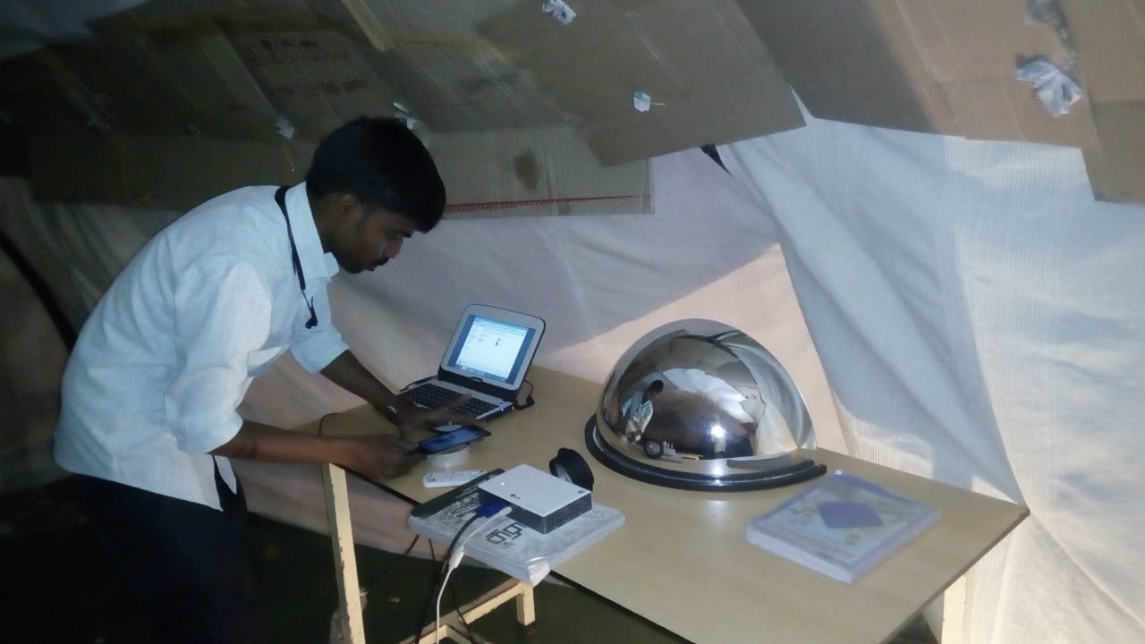 A student operating a laptop and phone to test the star-projection display inside the finished dome