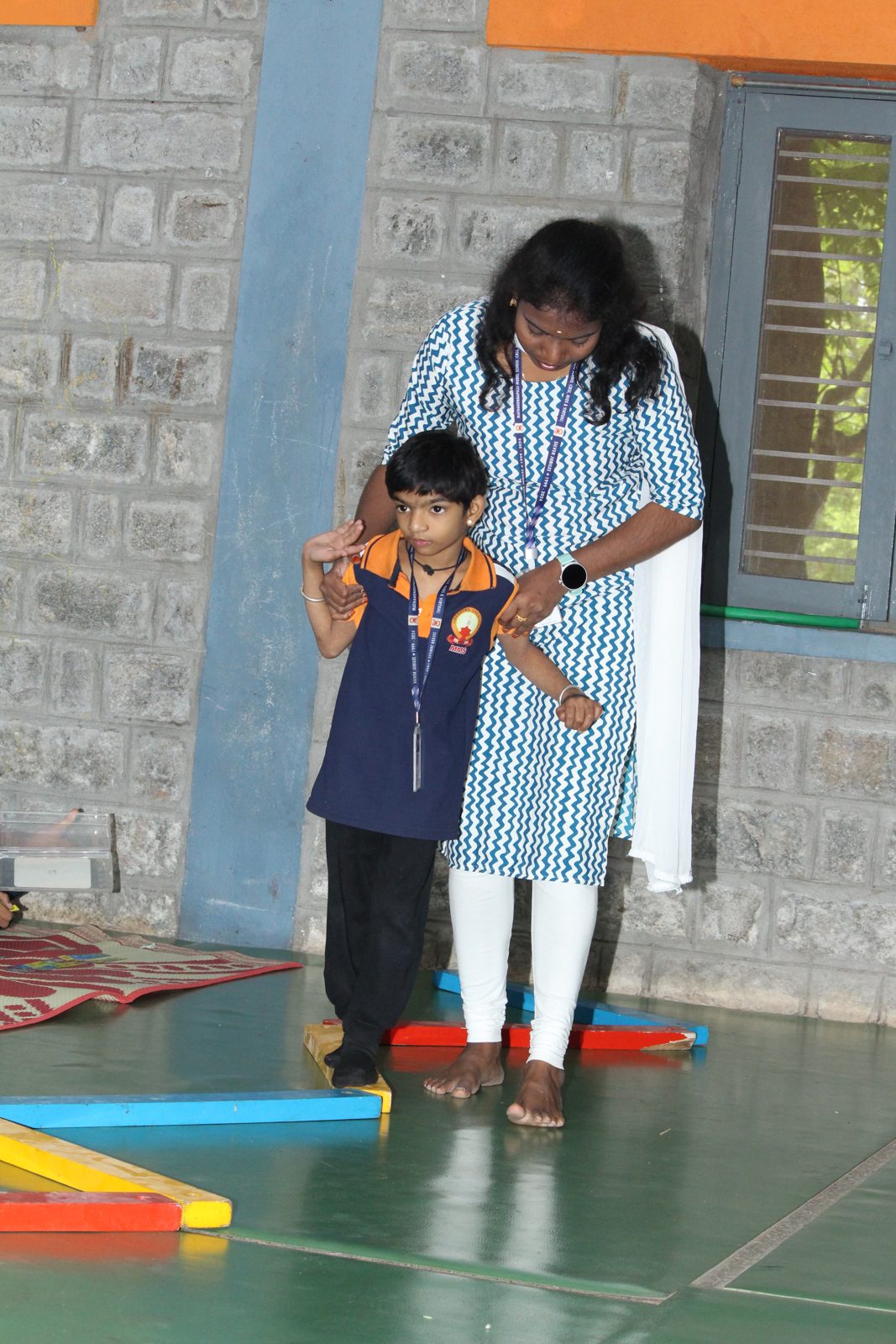 An educator supporting a child stepping along a balance beam