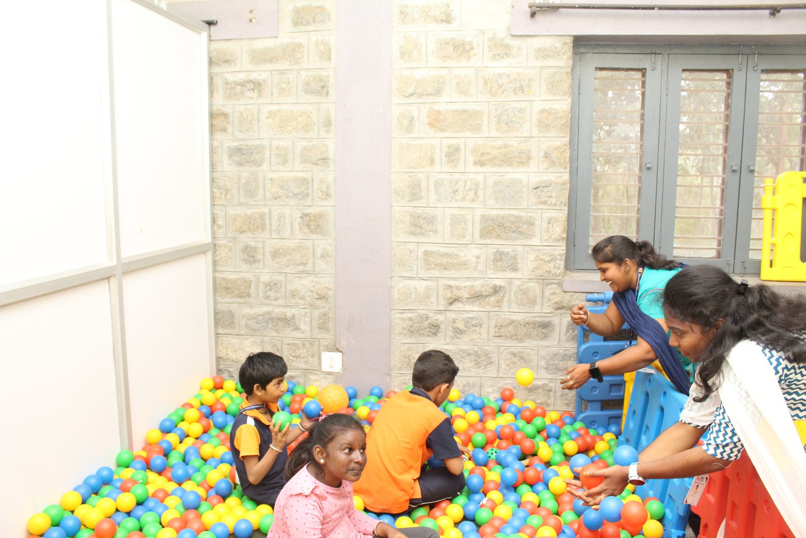 Children and educators around a ball pit in the play area