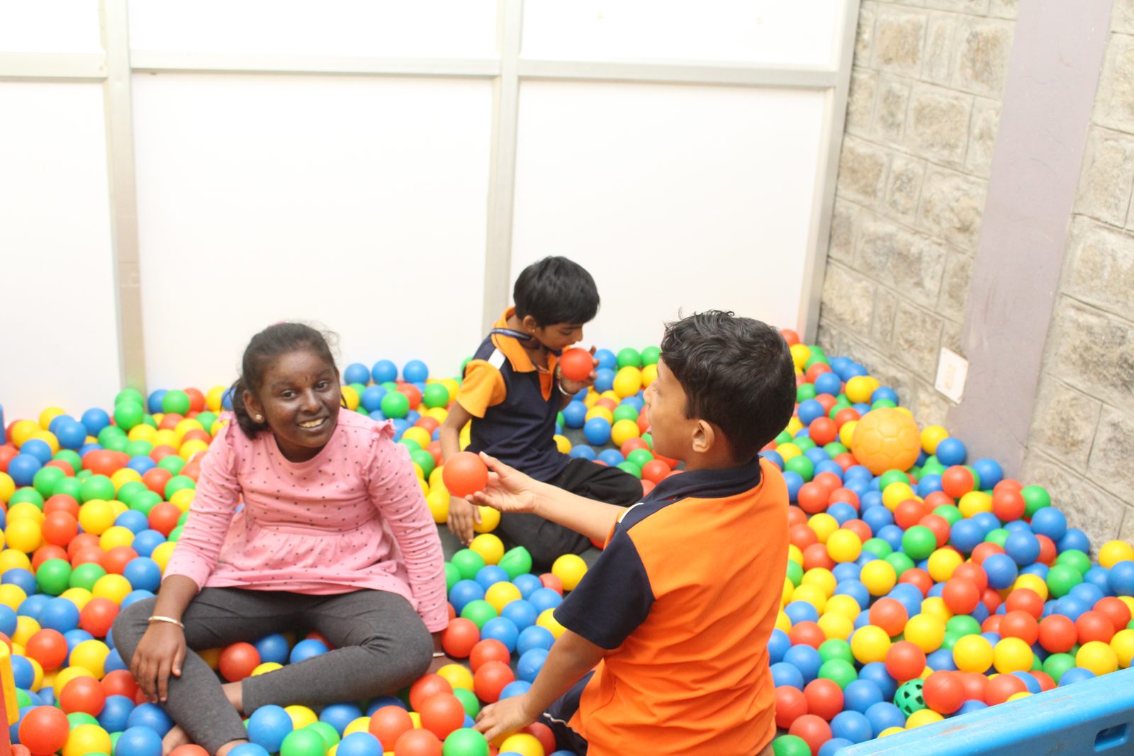 Children playing and sharing balls together in a colourful ball pit