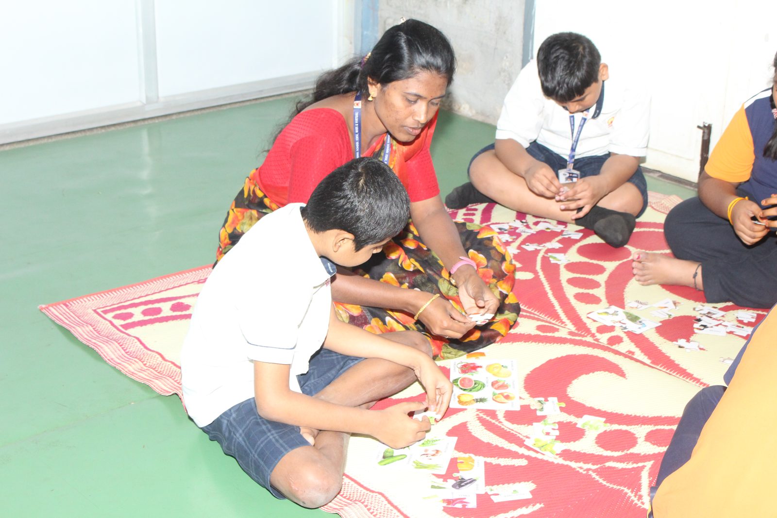 An educator and students matching picture cards on a floor mat
