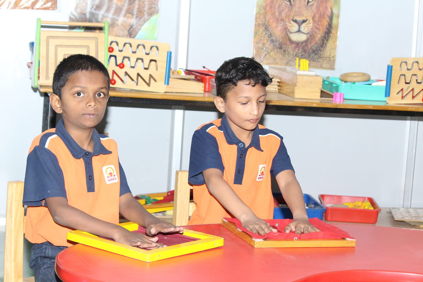Two students pressing their hands on tactile frames at a table