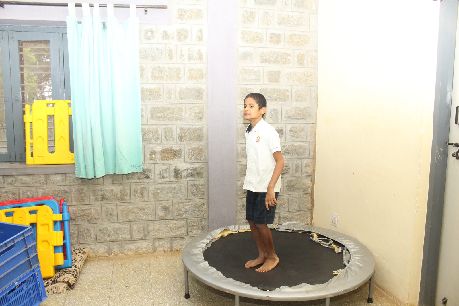 A child standing on a small trampoline in an activity room