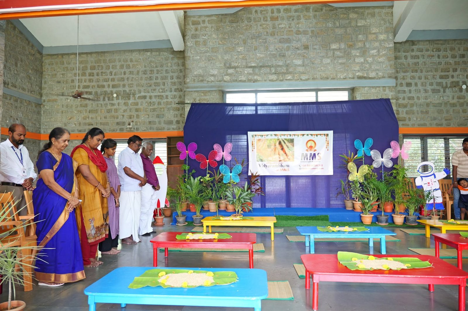 Teachers and guests standing together in the decorated hall at the start of the Vidhyarambam ceremony